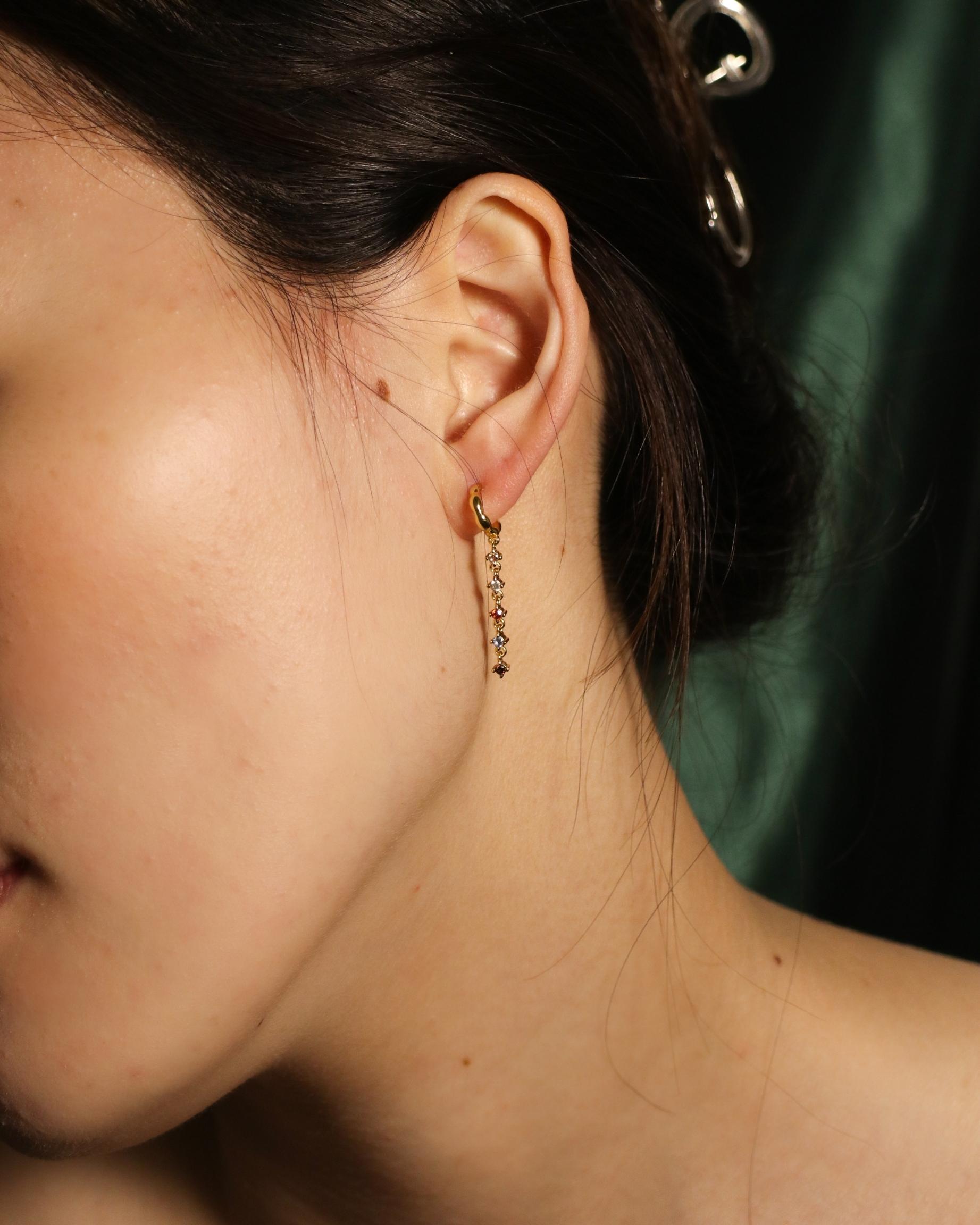 woman wearing dangling colourful zirconia open hoop earrings