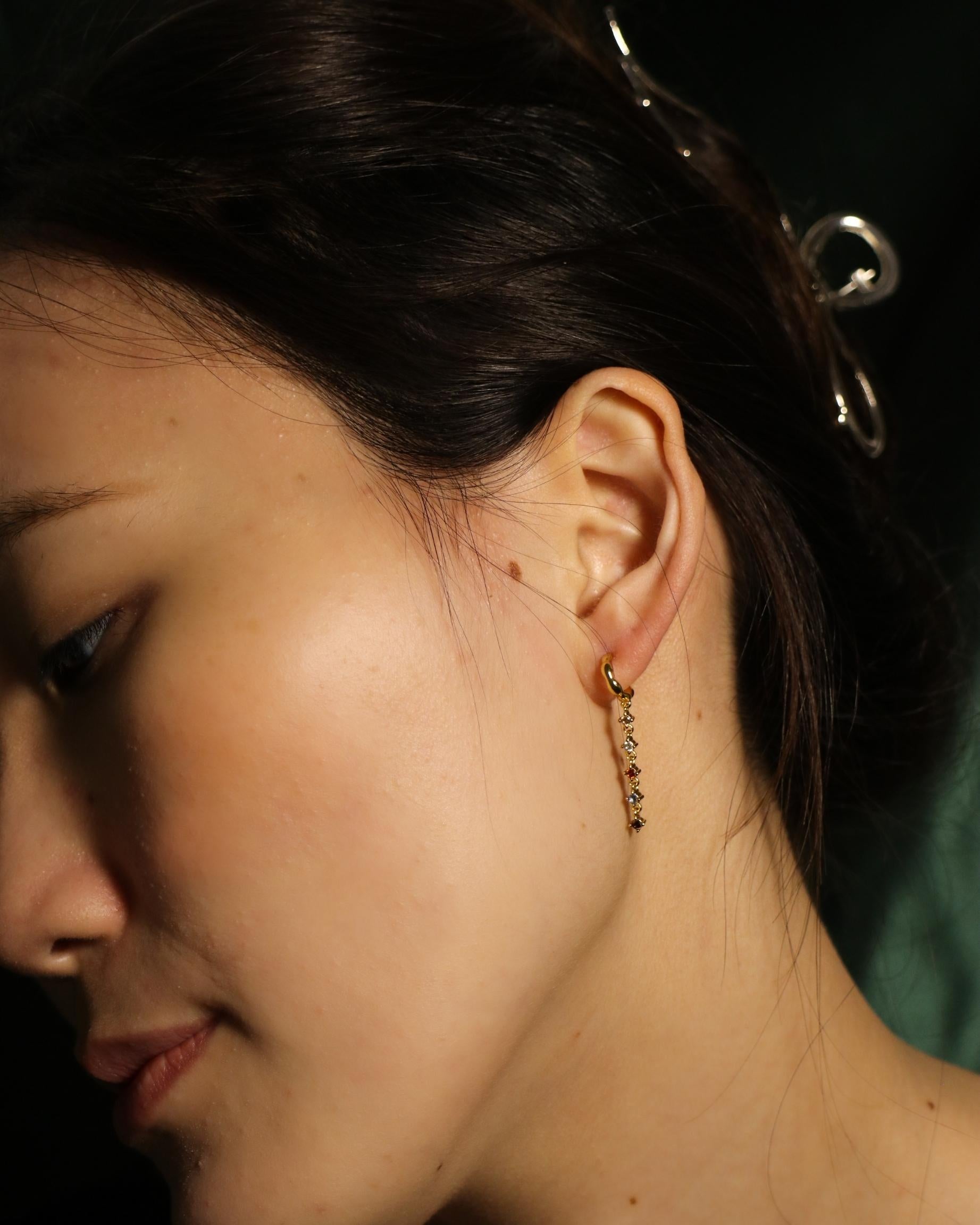 woman wearing dangling colourful zirconia open hoop earrings