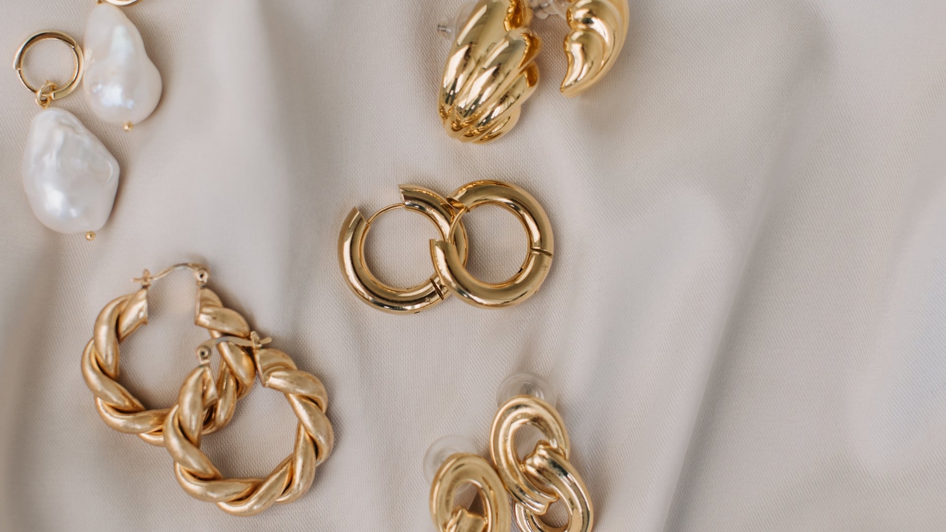 gold earrings laid on white cloth