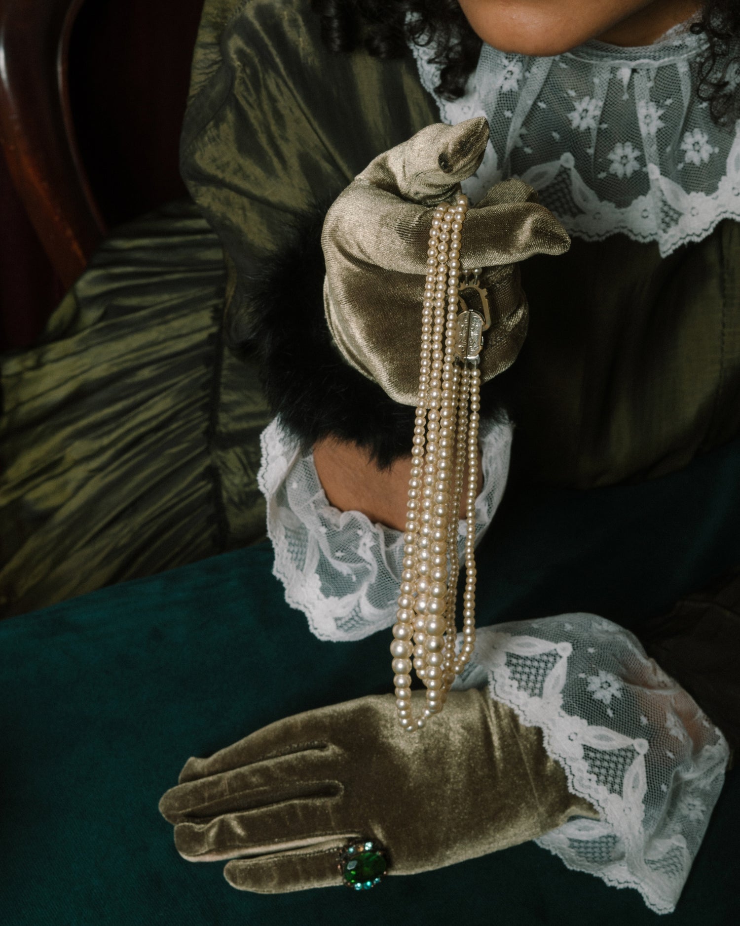 pearl necklaces held by model with green gloves