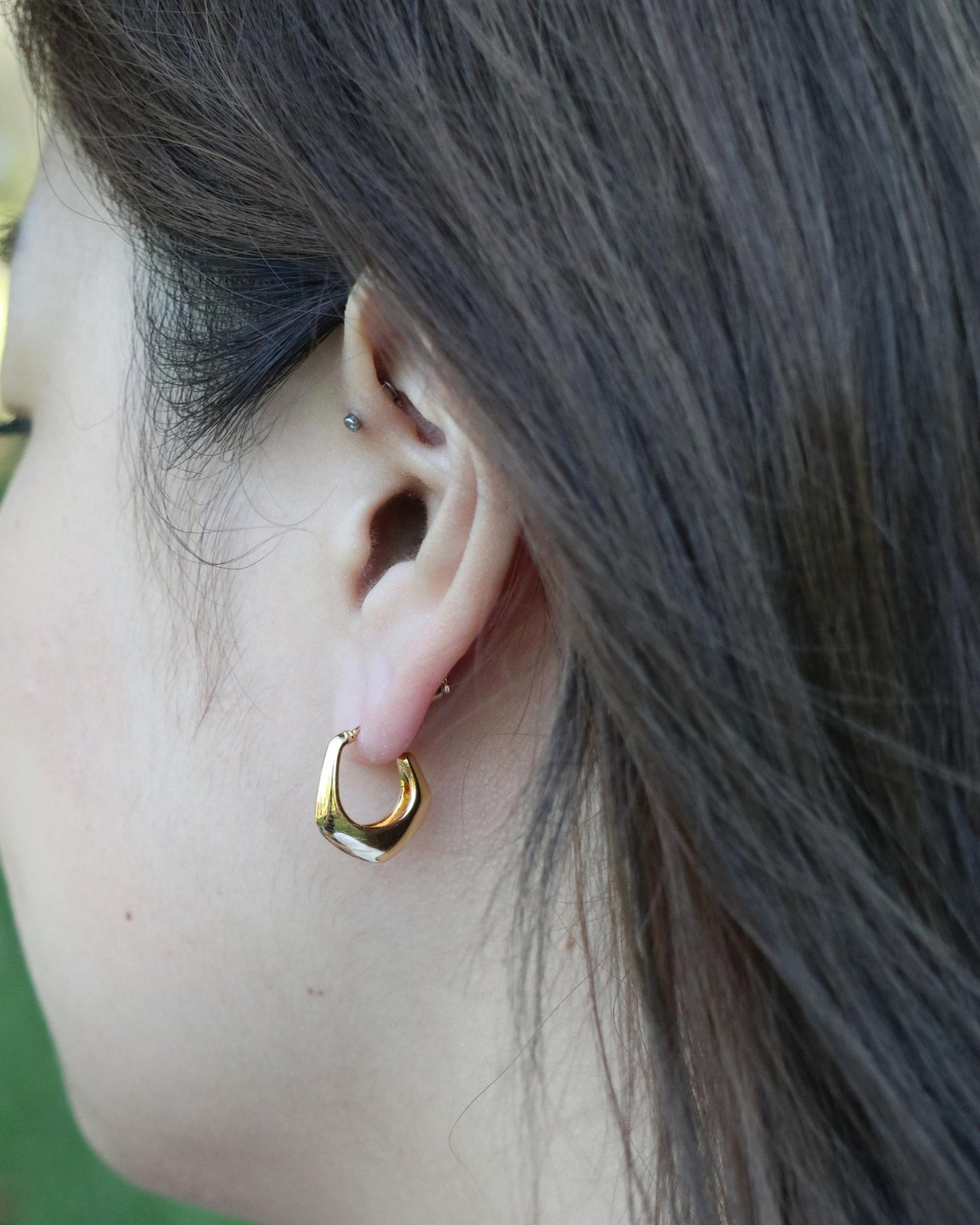 woman wearing geometric open hoop earrings