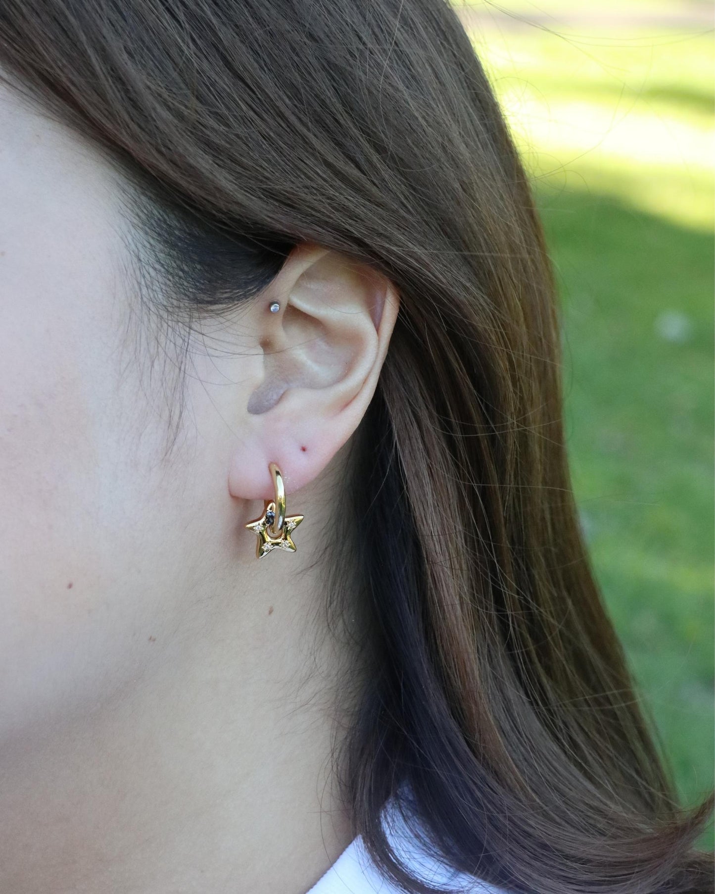 woman wearing gemstone star charm huggie earrings