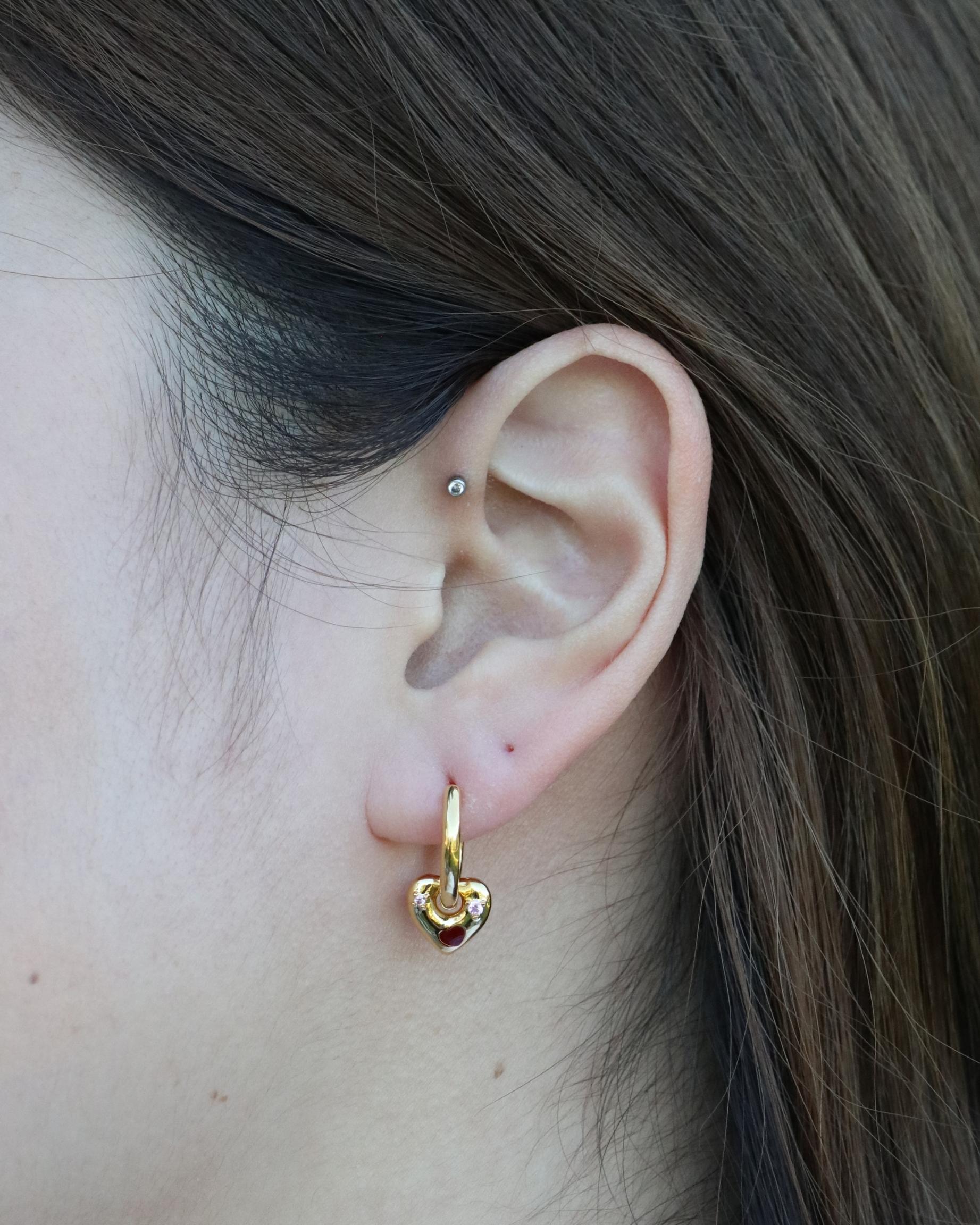 woman wearing gemstone heart charm huggie earrings