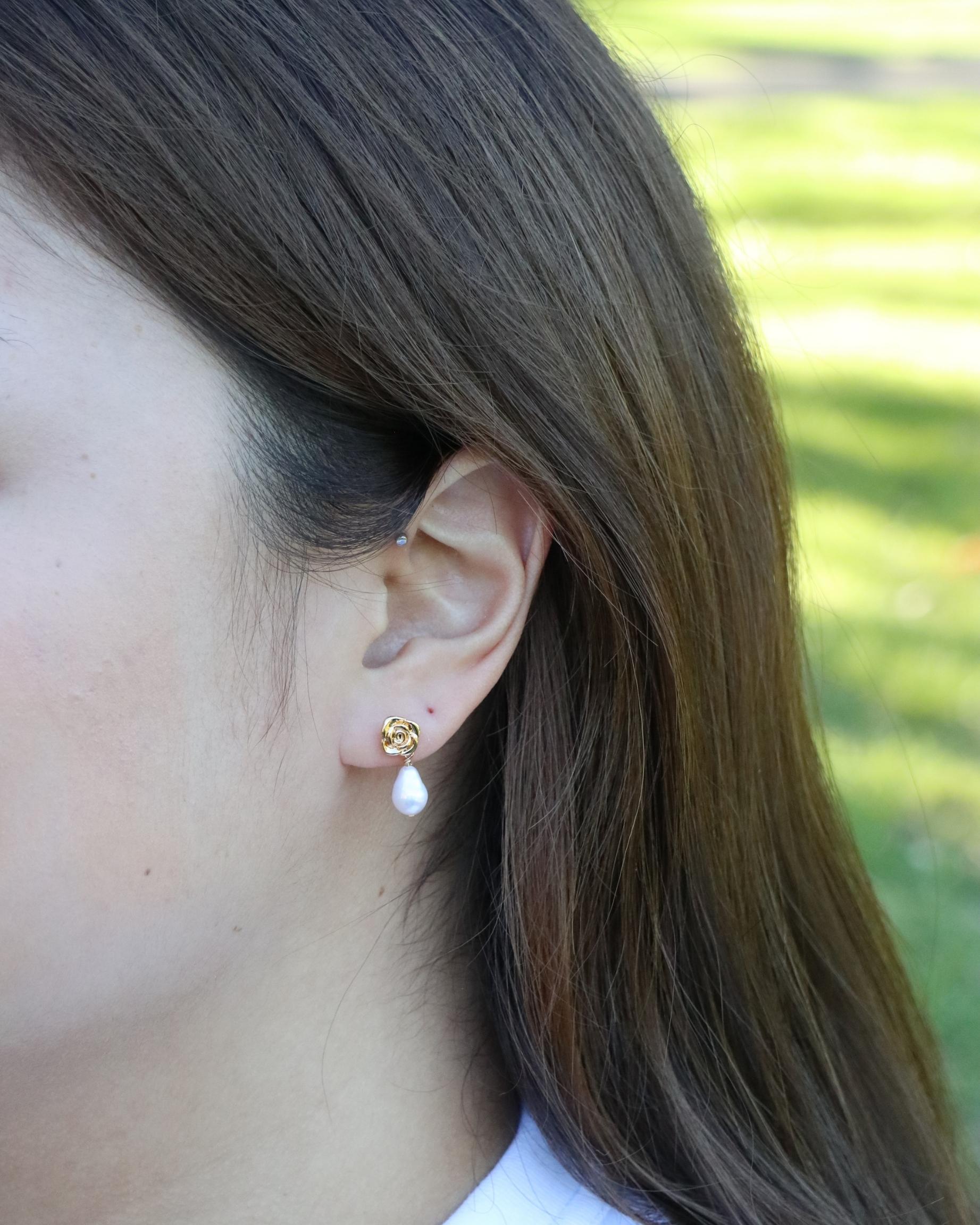 close up of drop pearl gold stud earrings