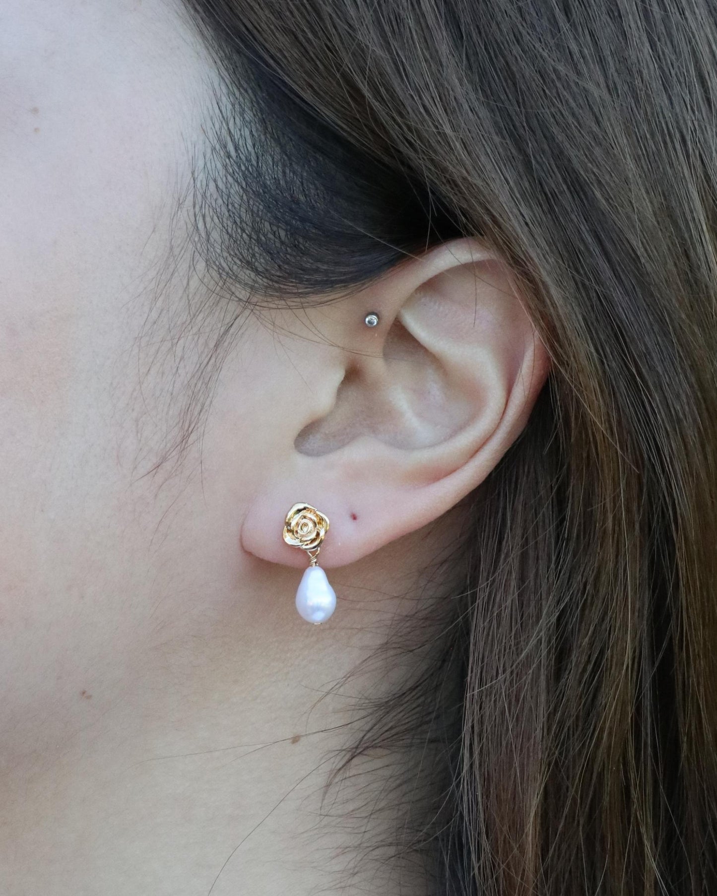 woman wearing drop pearl gold stud earrings